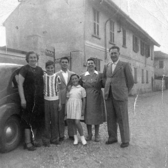 Een vintage portret van volwassenen en kinderen die poseren voor een oude auto en huis