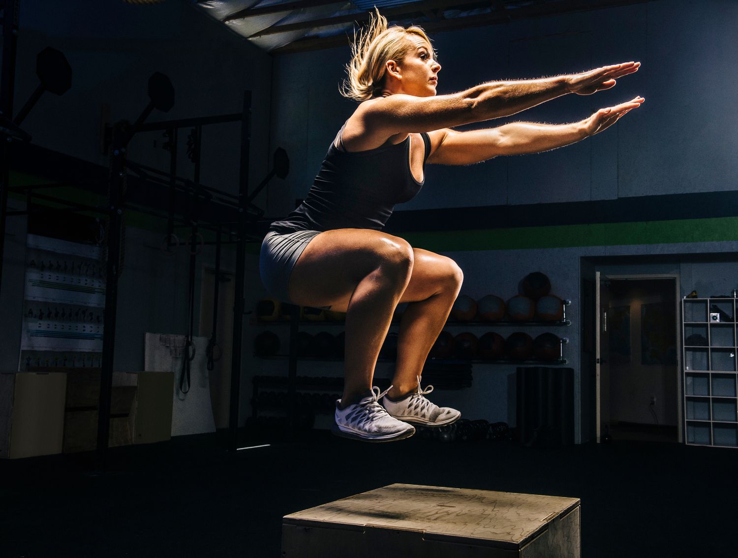 Vrouw die op een doos in de sportschool springt