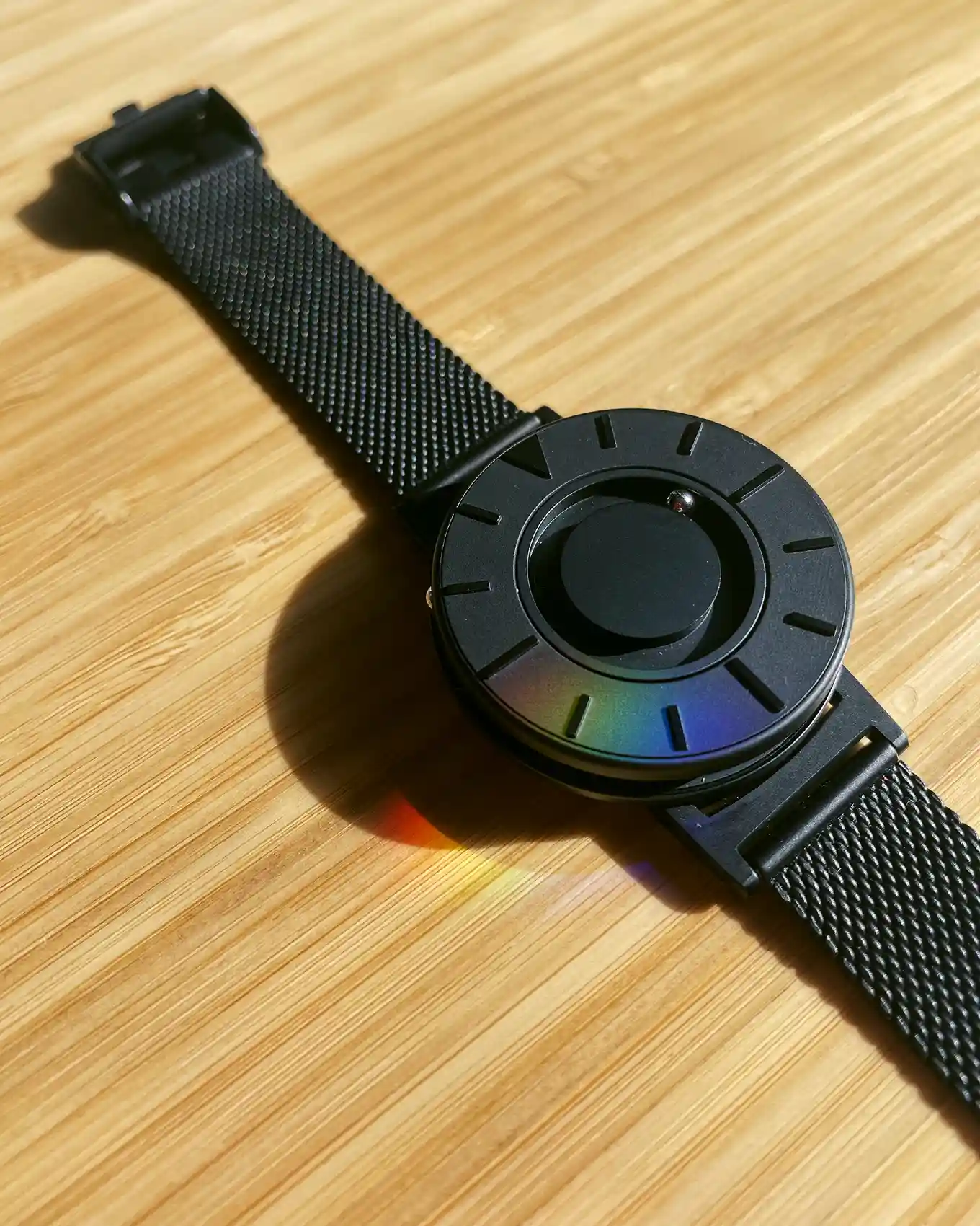 Close-upweergave van het Bradley-horloge, dat minimalistisch van ontwerp is, allemaal matzwart en twee kleine ballen heeft die rond het horloge draaien om de tijd weer te geven