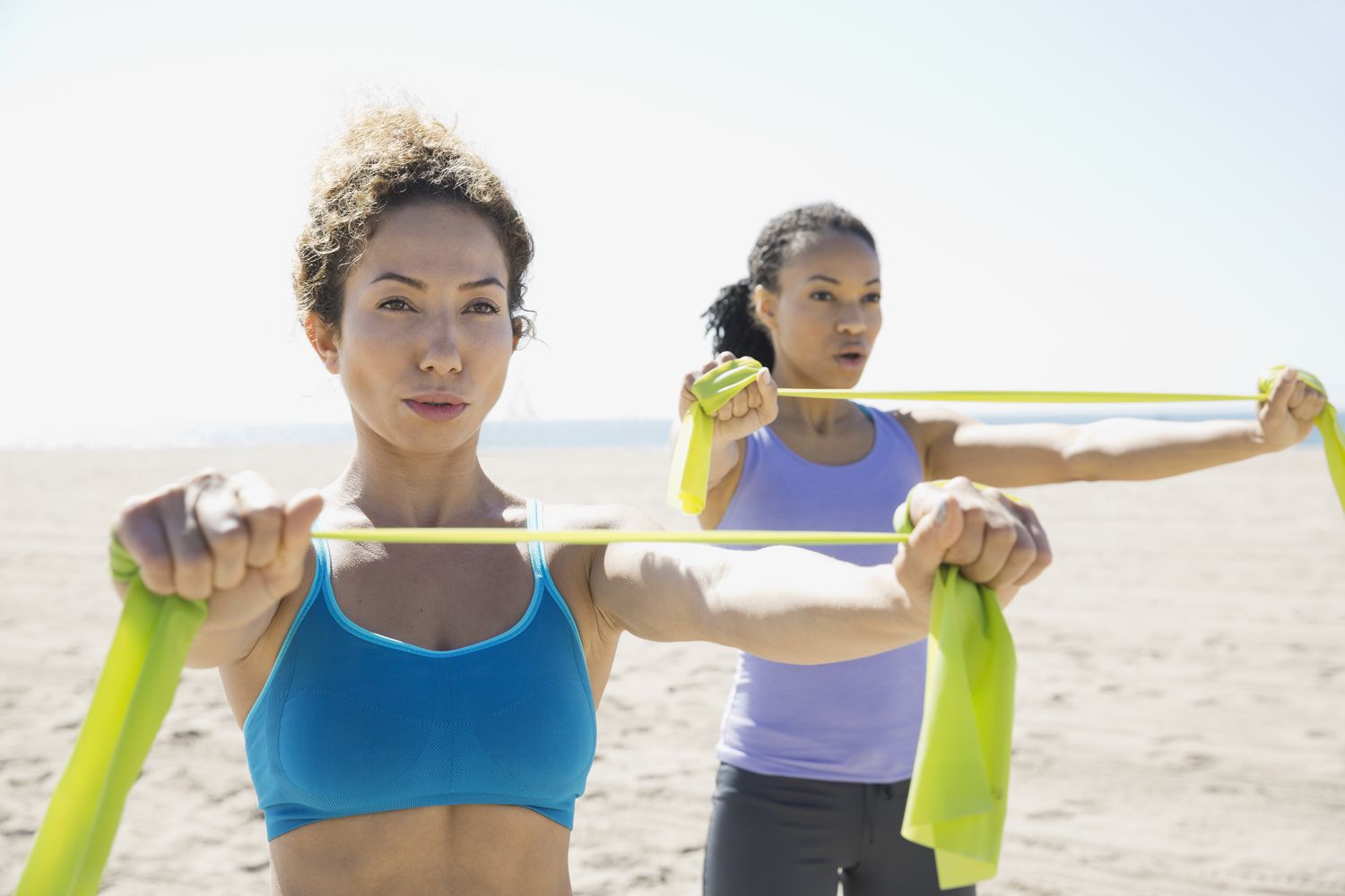 Vrouwen die met weerstandsband op het strand sporten
