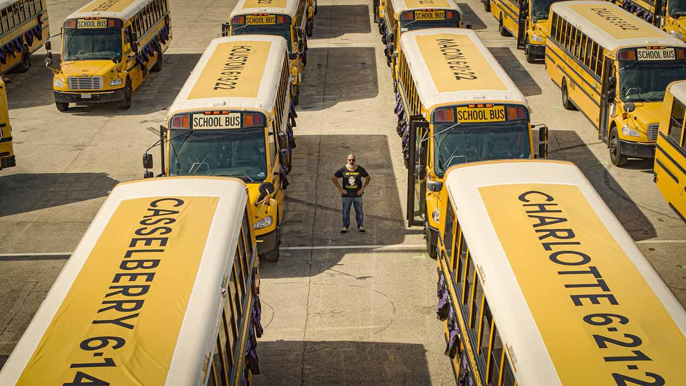 Manuel Oliver, staande tussen gele schoolbussen
