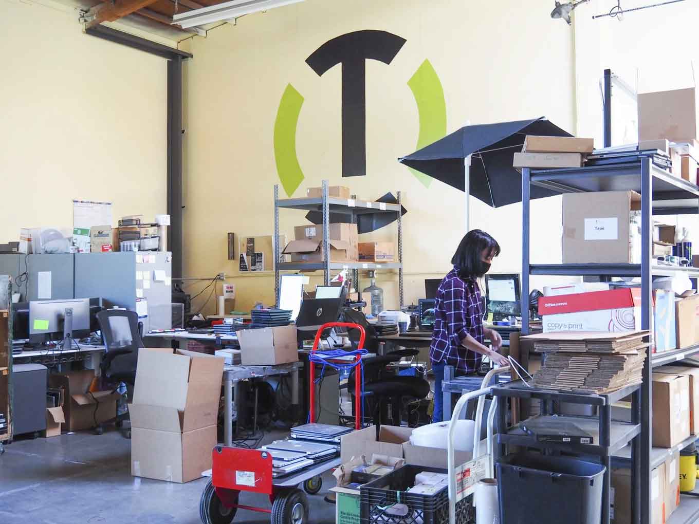 Een Tech Exchange-medewerker werkt in mei 2021 in het magazijn van de non-profitorganisatie. Zij en haar collega's werkten maandenlang aan #OaklandUndivided apparaten.