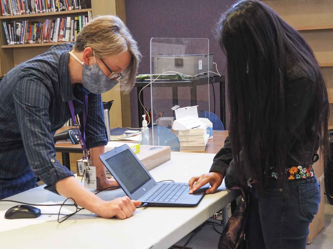 Jen Bender, de data tech lead op Castlemont High School, geeft een nieuwe student haar #OaklandUndivided Chromebook en hot spot in mei 2021. 