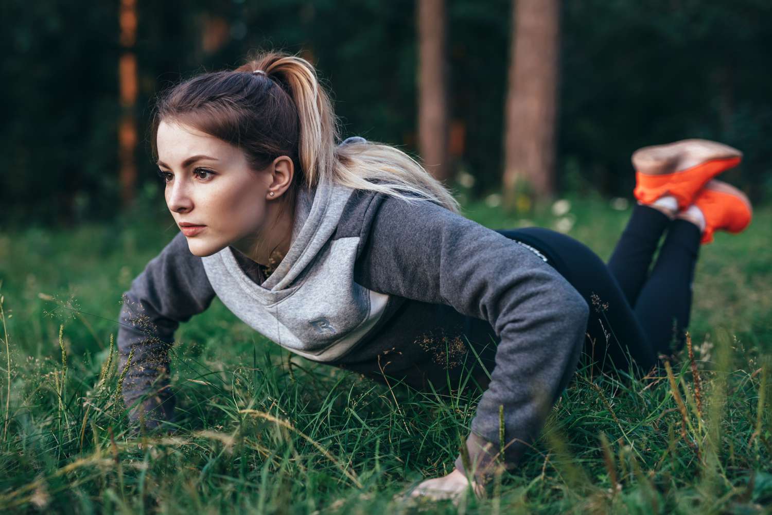Vrouw die traint op gras in park en knie push-ups doet