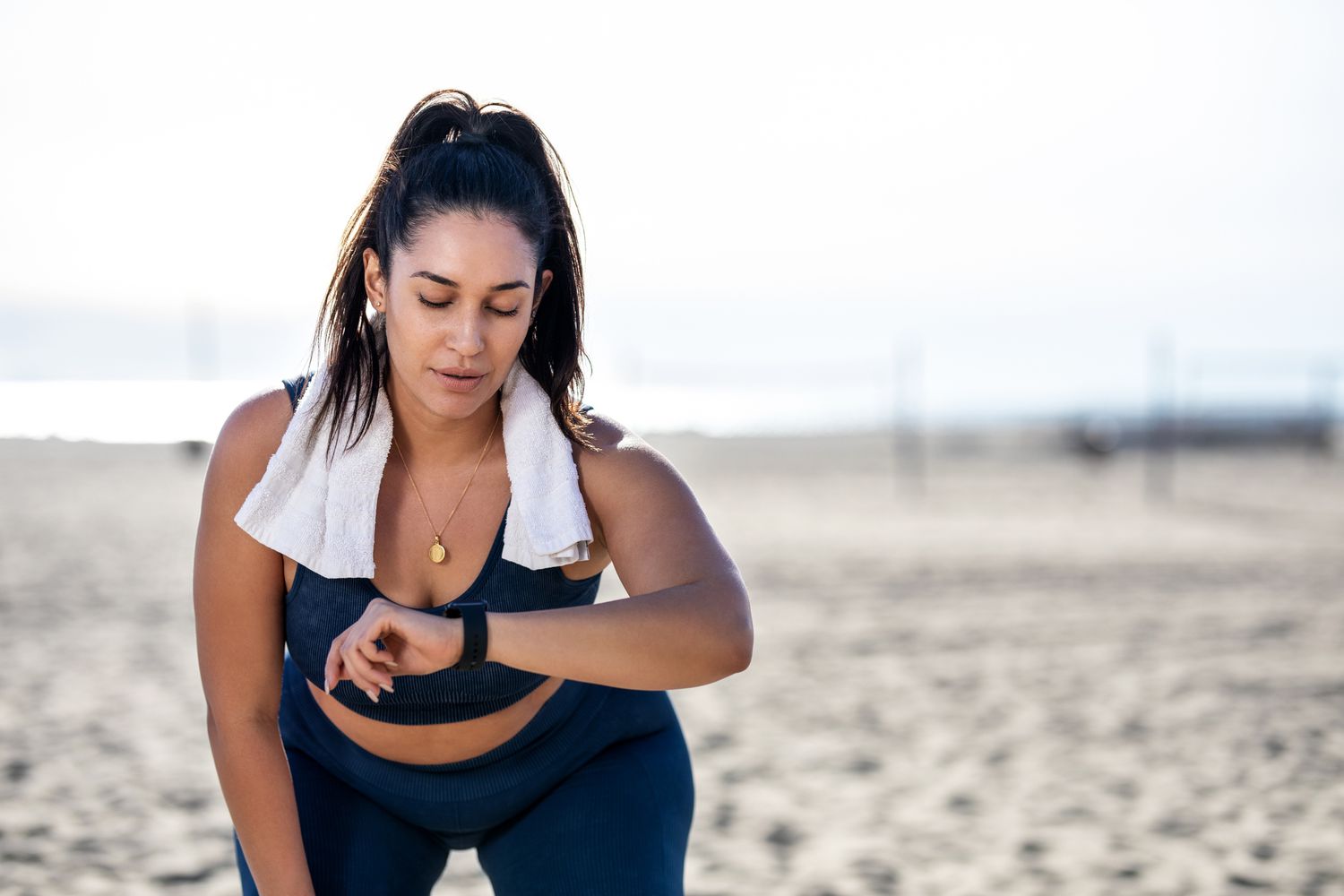 vrouw die fitnesshorloge controleert tijdens het trainen op het strand